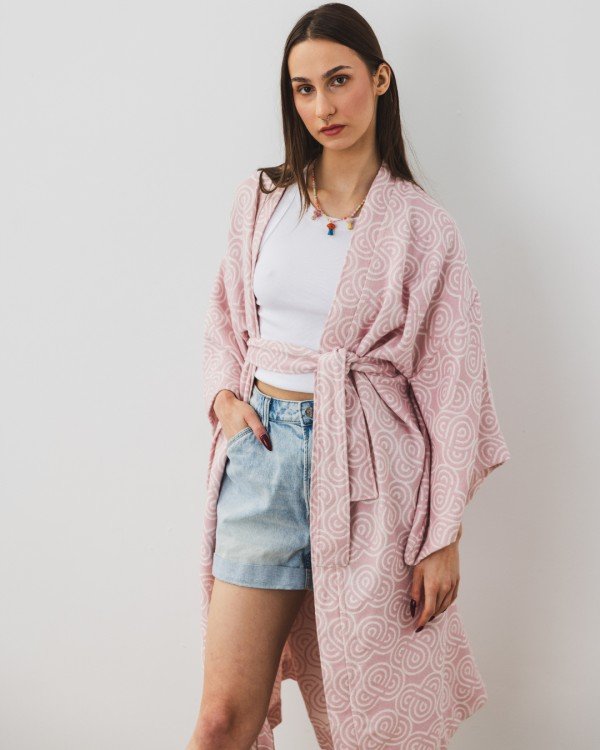 8. Woman wearing Patulove rose bamboo kimono with white top and denim shorts, standing against a white wall