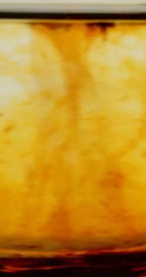 3. Close-up of swirling amber liquid representing rich rum note in perfume