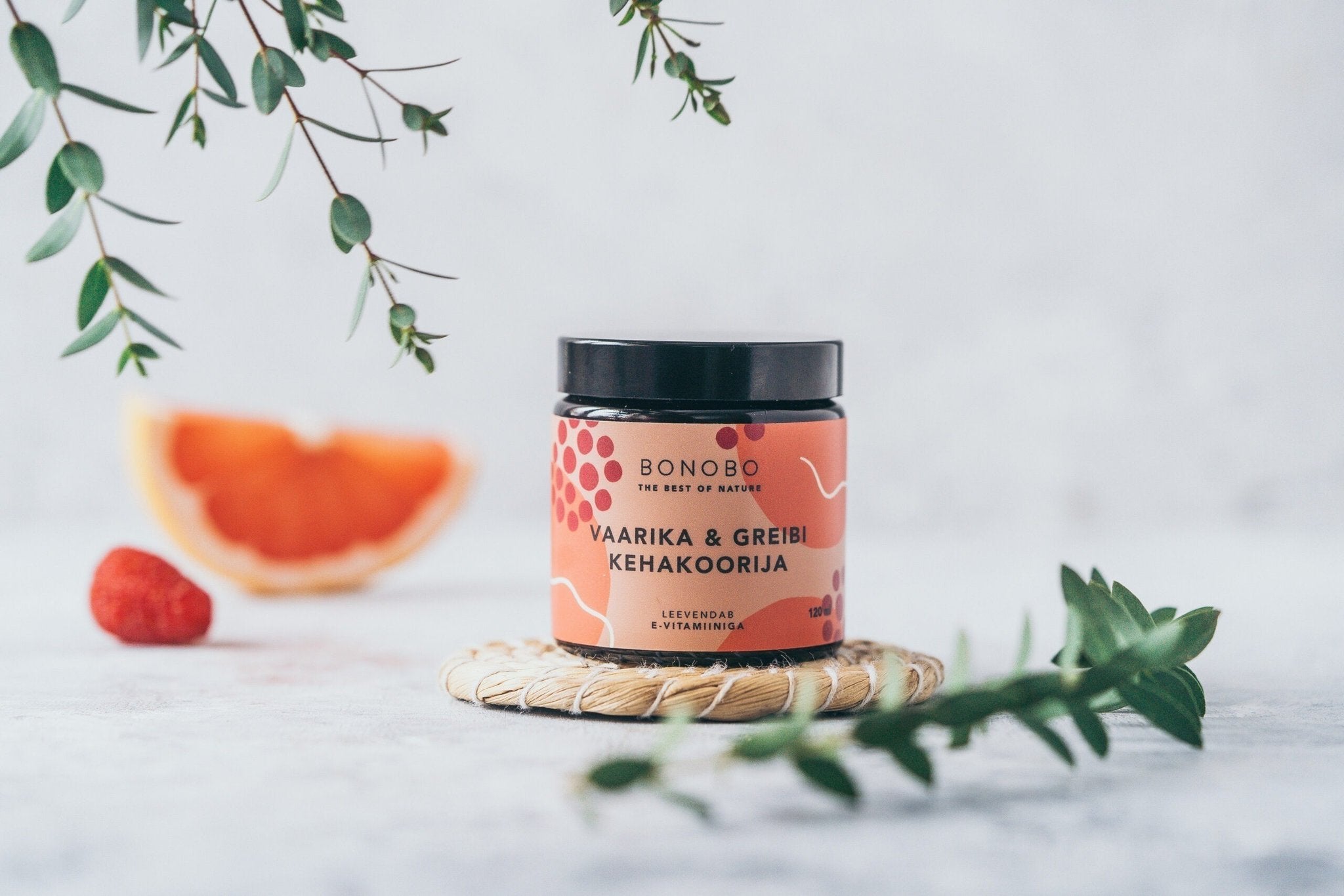 2. BONOBO Raspberry & Grapefruit body scrub jar on a woven mat with raspberry and grapefruit slice