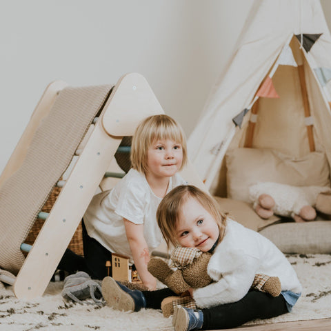 2. Two children playing near pastel Pikler Triangle and teepee in playroom