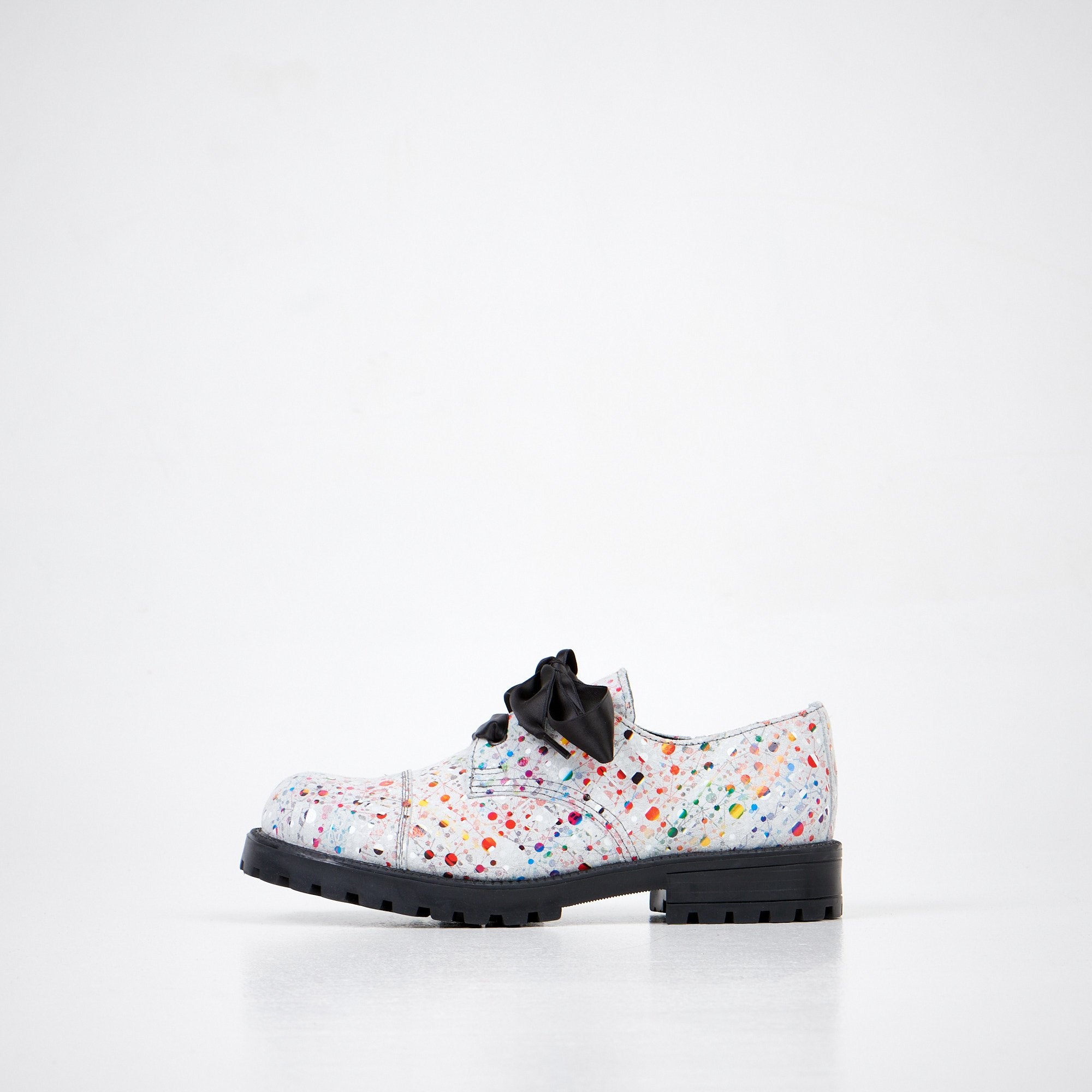 1. Unisex Samelin Dotted Widgets sneakers in white with colorful dots and black bow, side view in studio