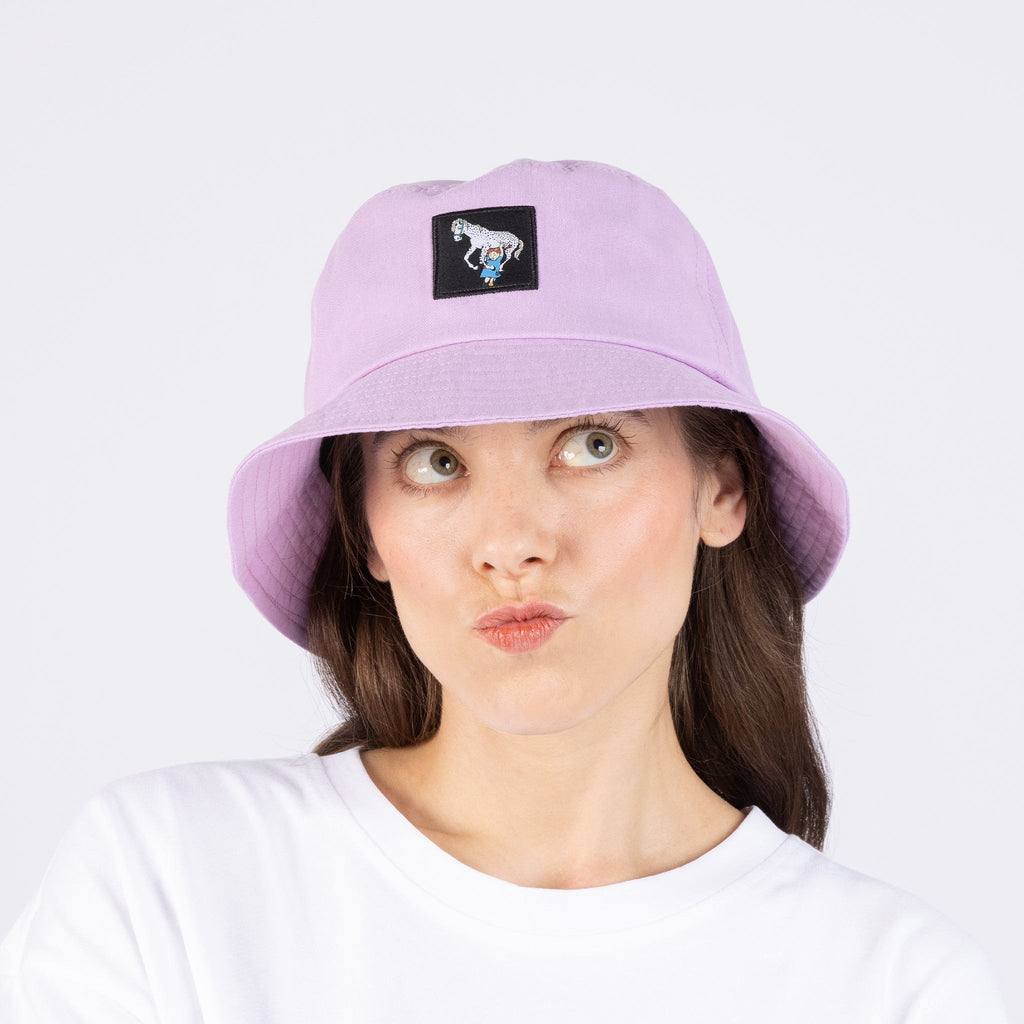 1. Woman wearing lilac Pippi Longstocking bucket hat with embroidered patch, posing playfully against white background