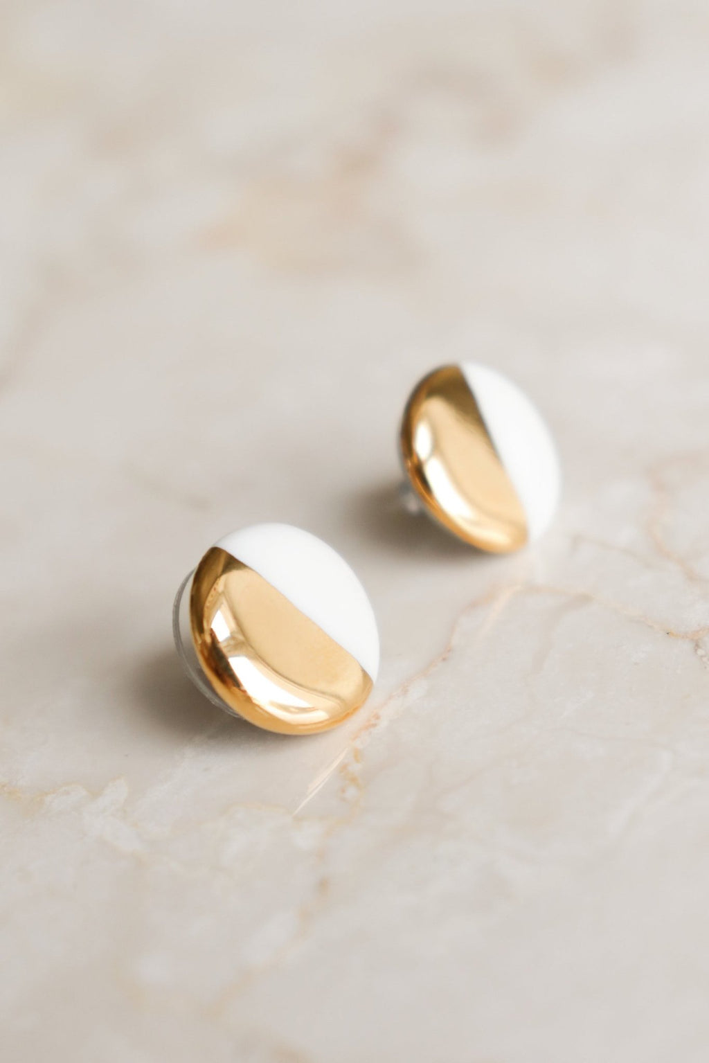 5. Close-up of Rozenthal porcelain round stud earrings in white and gold, showing sterling silver studs