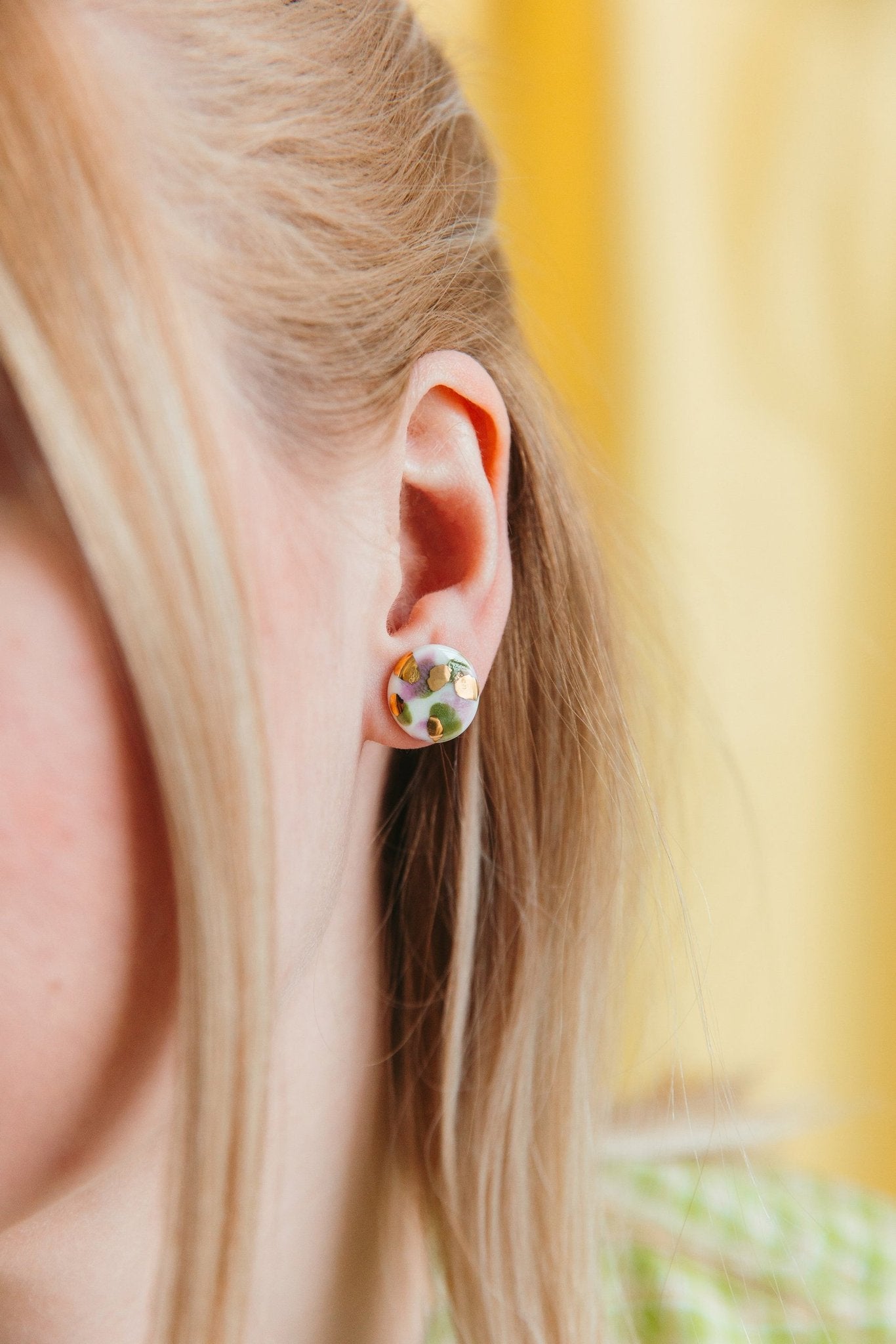 1. Woman wearing Rozenthal Porcelain Tache Studs in blue and orange with 24k gold accents, shown in lifestyle setting