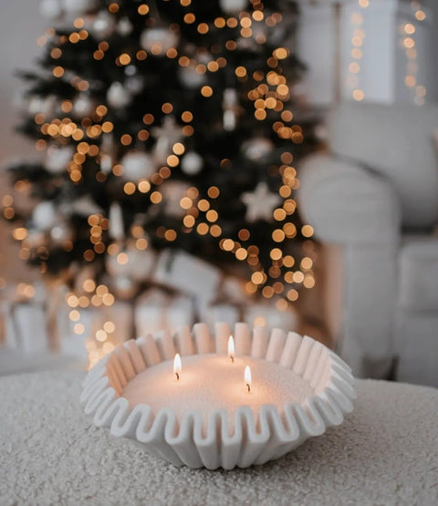 1. White sand candle with three flames in a decorative bowl in front of a Christmas tree