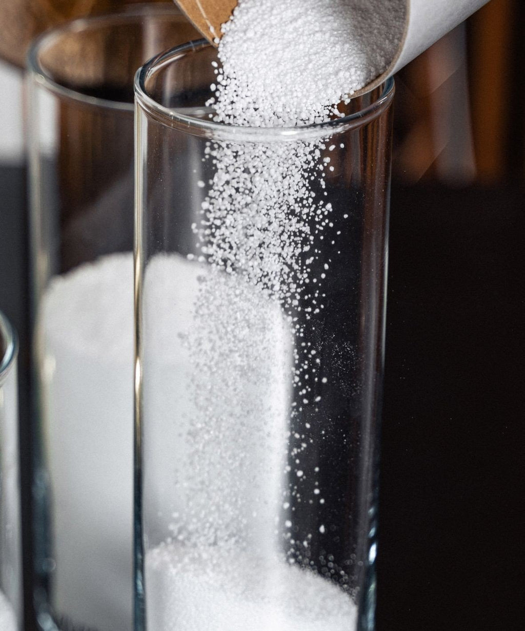 3. Close-up of white Candledust powder being poured into a tall glass container