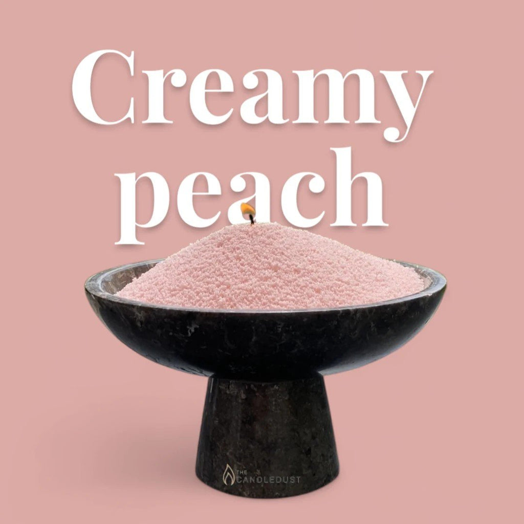 1. Candledust creamy peach candle sand in black bowl with lit wick and large text on pink background
