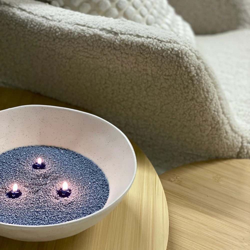 1. Three lit wicks in a bowl of dark blue Candledust on a wooden table, cozy setting with a textured blanket