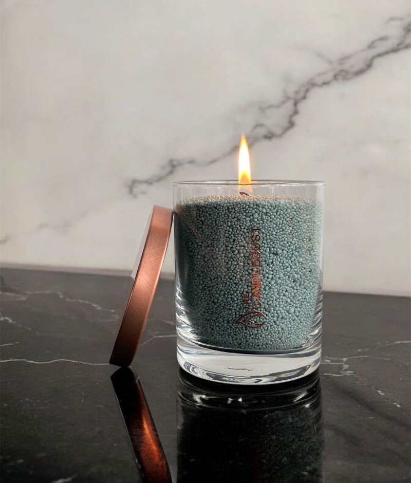 1. Candledust emerald powdered candle in a glass jar with a lit wick on a marble surface