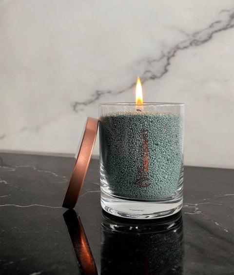 1. Candledust emerald powdered candle in a glass jar with a lit wick on a marble surface