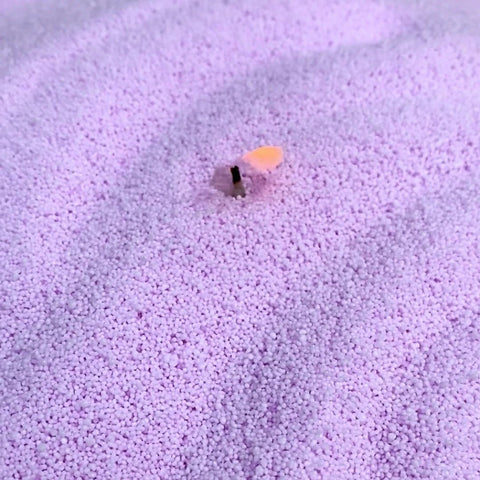 3. Close-up of light lilac candle sand with a wick inserted, showcasing fine-grained texture