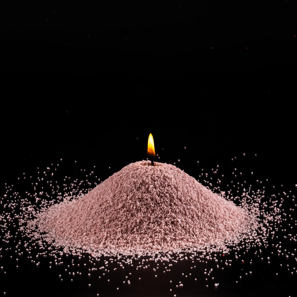 2. Burning pile of nude-colored candle sand on black background