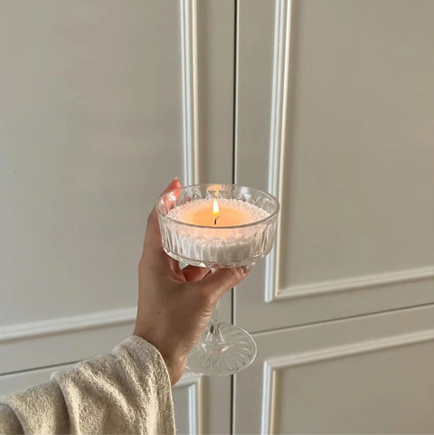 1. Woman holding a lit candle in a glass container, showcasing the powdered candle refill kit in a cozy indoor setting