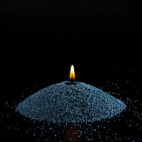 2. Mound of space grey candle sand with lit wick on black background