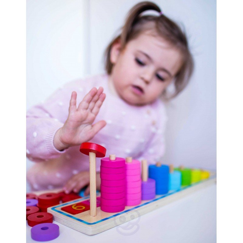 9. Child in pink polka dot sweater stacking red rings on a wooden counting puzzle