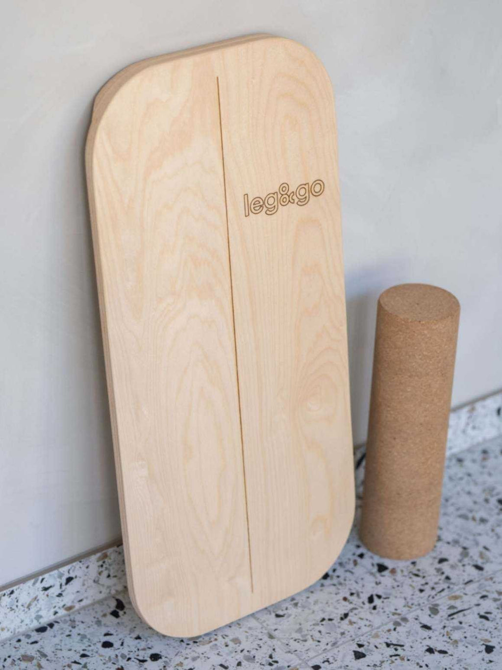 1. Rectangular balance board with cork roller featuring leg&go side logo on terrazzo floor