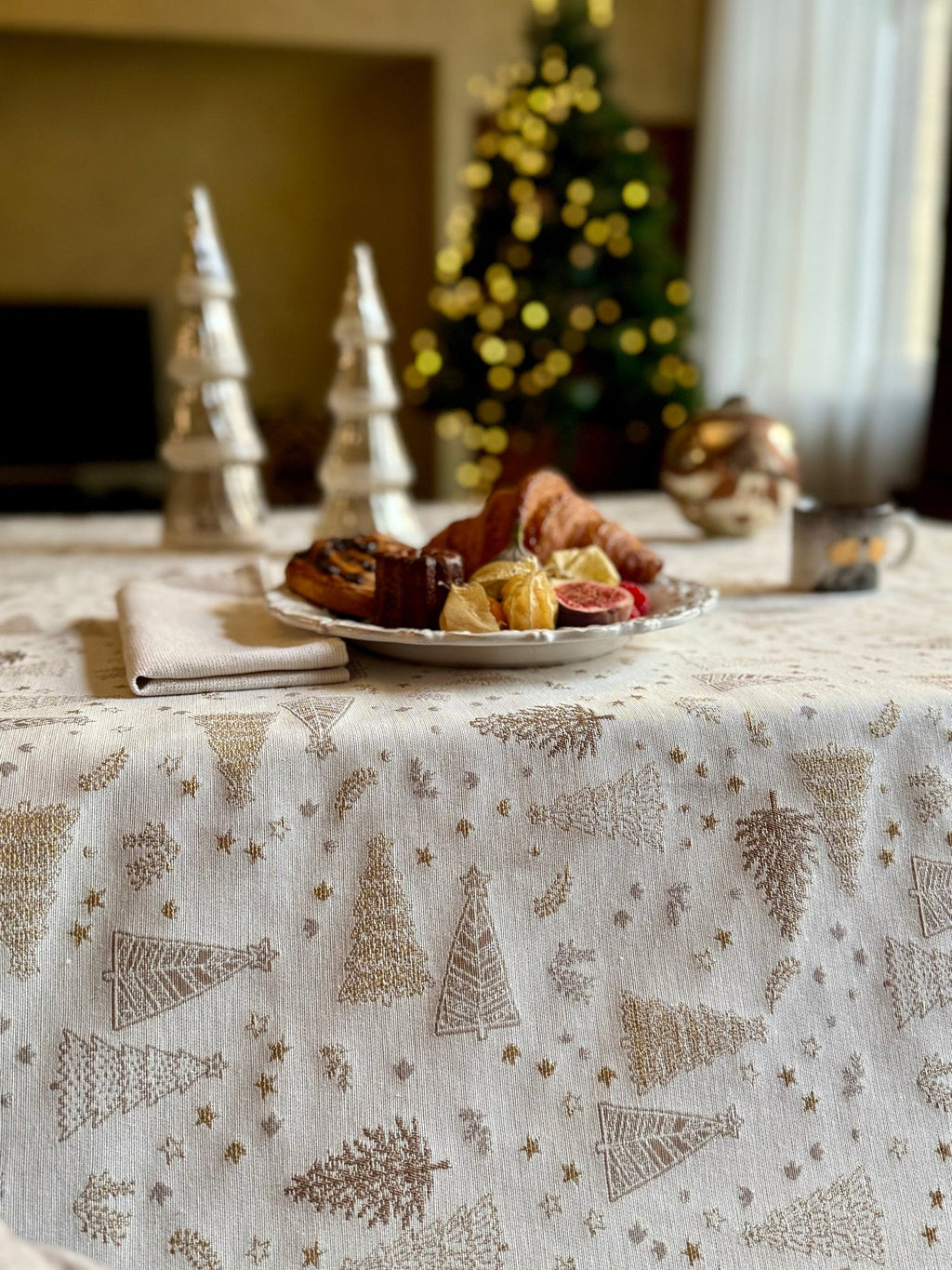1. Elegant dining table with Hortensias Home Golden Forest tablecloth featuring golden fir motifs, set with pastries and Christmas decor in cozy room