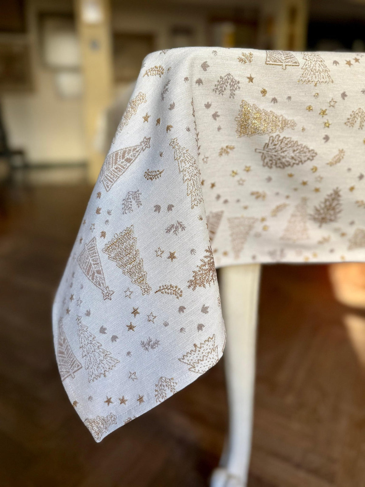 4. Corner view of Hortensias Home Golden Forest tablecloth draped over table, highlighting golden fir motif and soft fabric texture
