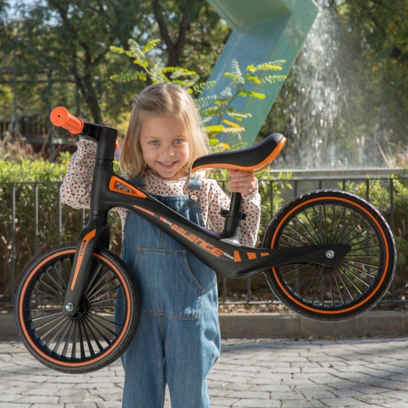1. Smiling girl holding Feber balance bike in a park