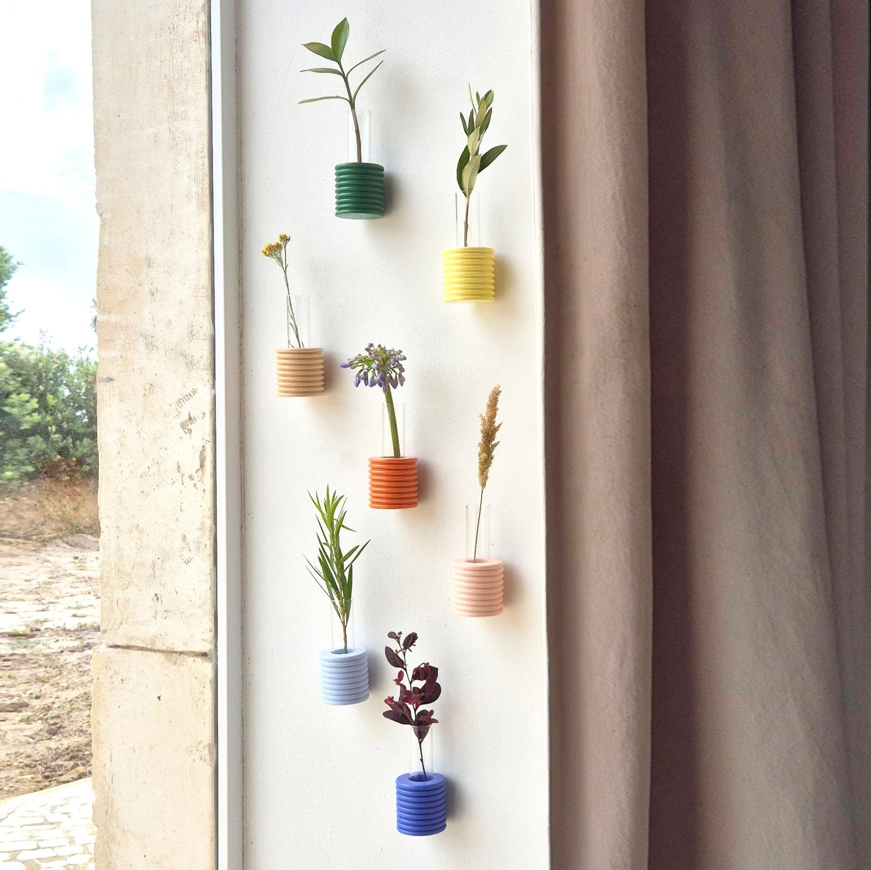 4. Collection of colorful Ribble Wall Vases on a wall, featuring various plants and vibrant hues