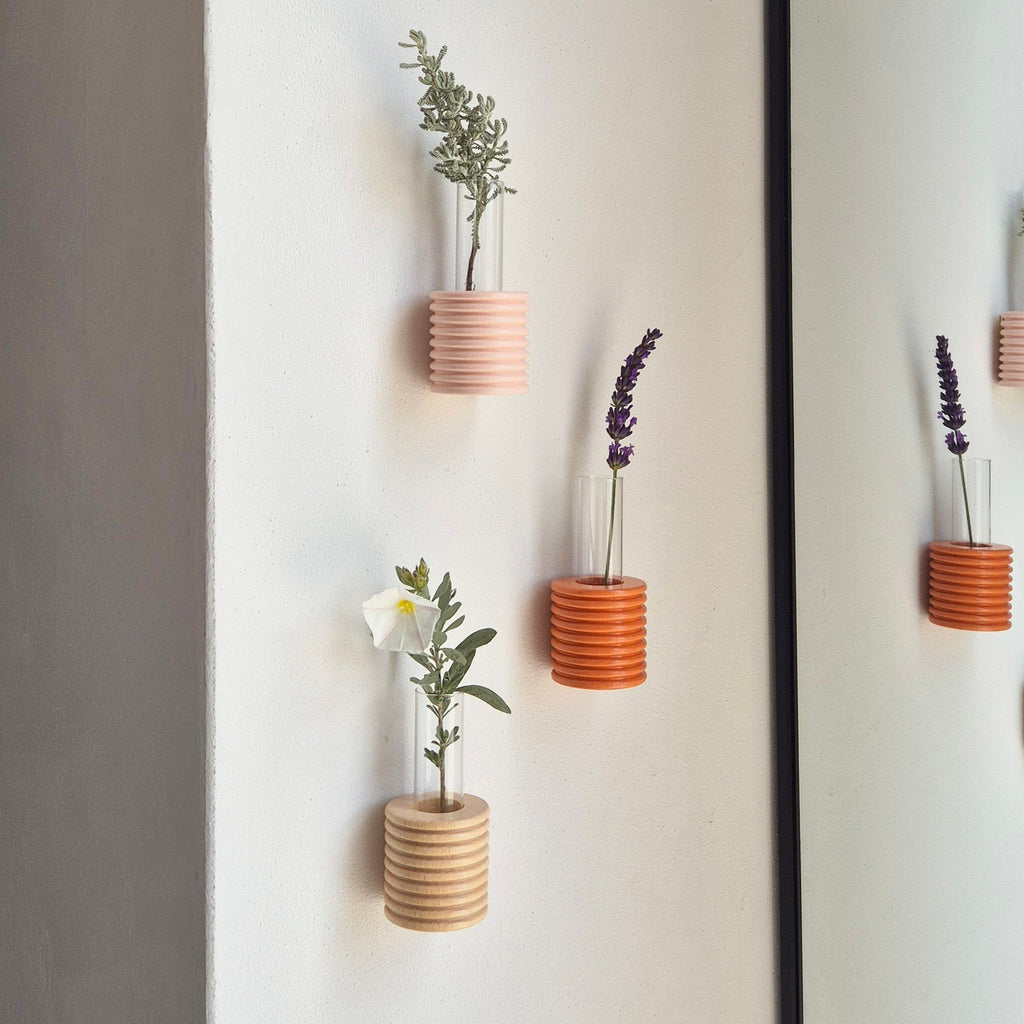 4. Lifestyle image of Ribble Wall Vases in pink and orange by 5mm Paper, displayed with flowers on a wall
