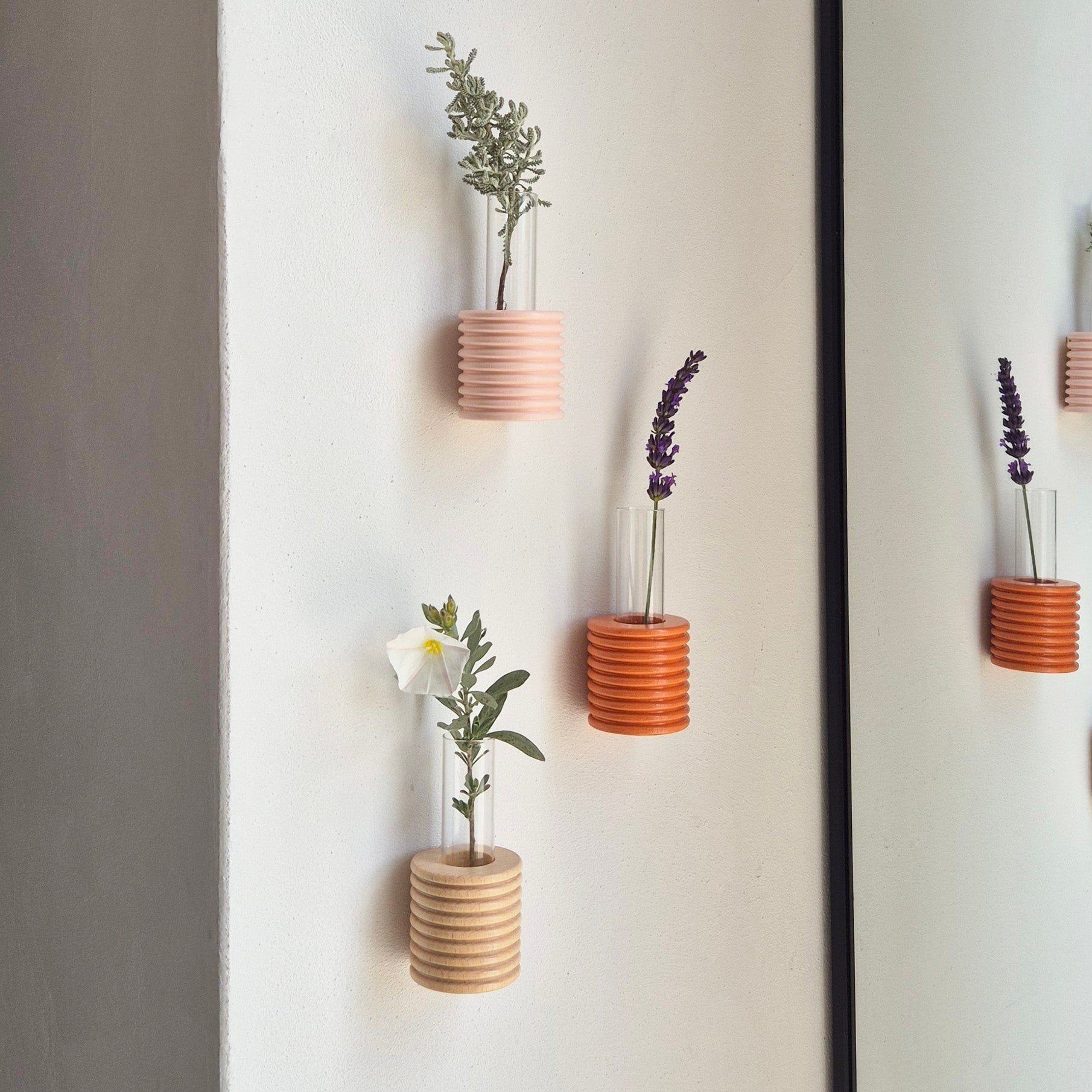2. Collection of Ribble Wall Vases in various colors by 5mm Paper, displayed on a wall with flowers, lifestyle setting