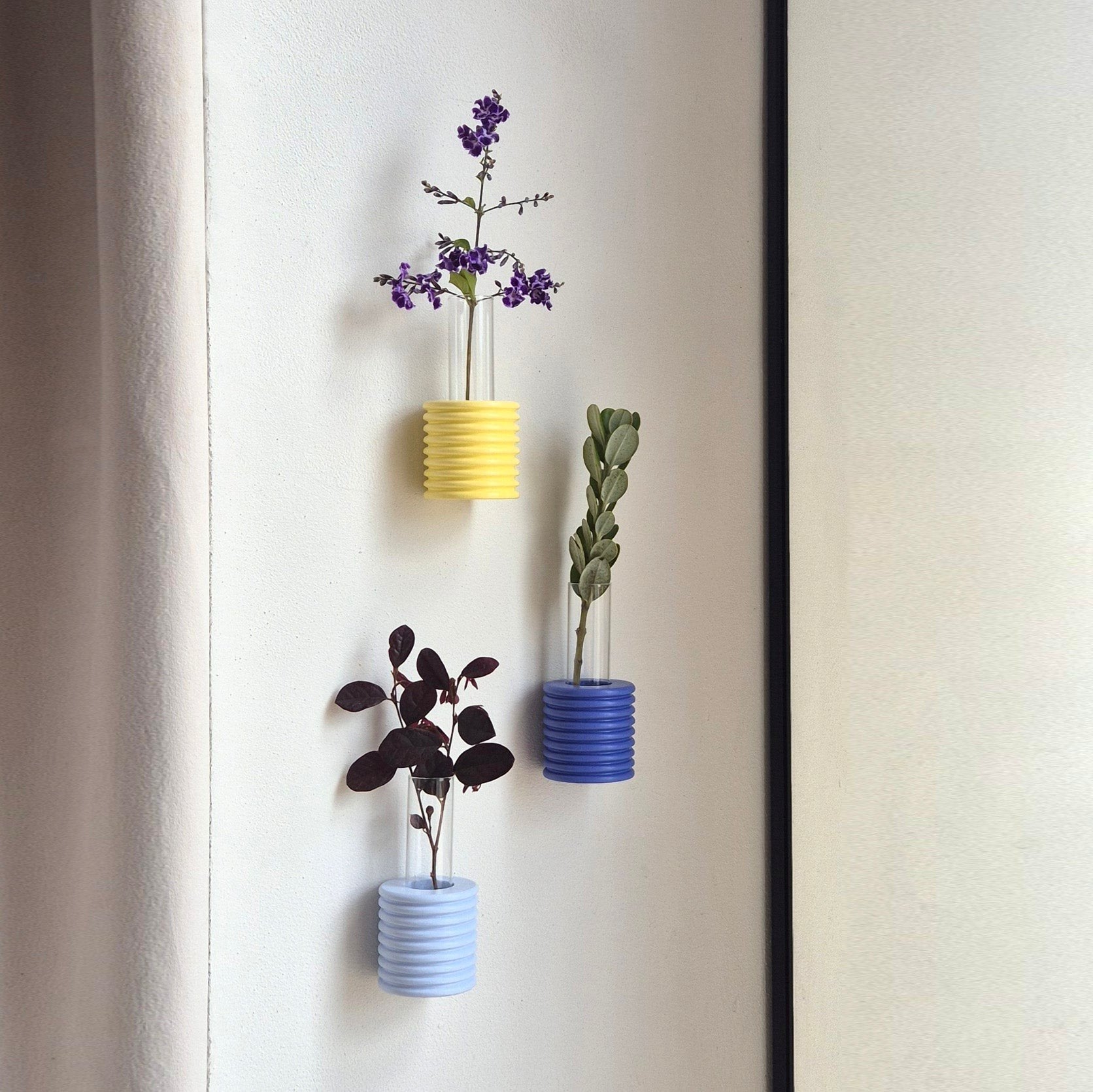 3. Yellow, blue, and purple Ribble Wall Vases by 5mm Paper, each with different flowers, lifestyle setting