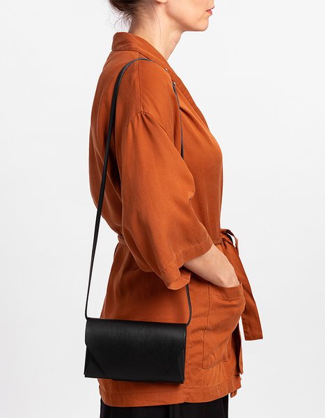 8. Woman wearing black leather Stella Soomlais Capital of Plenty clutch-wallet crossbody with orange jacket