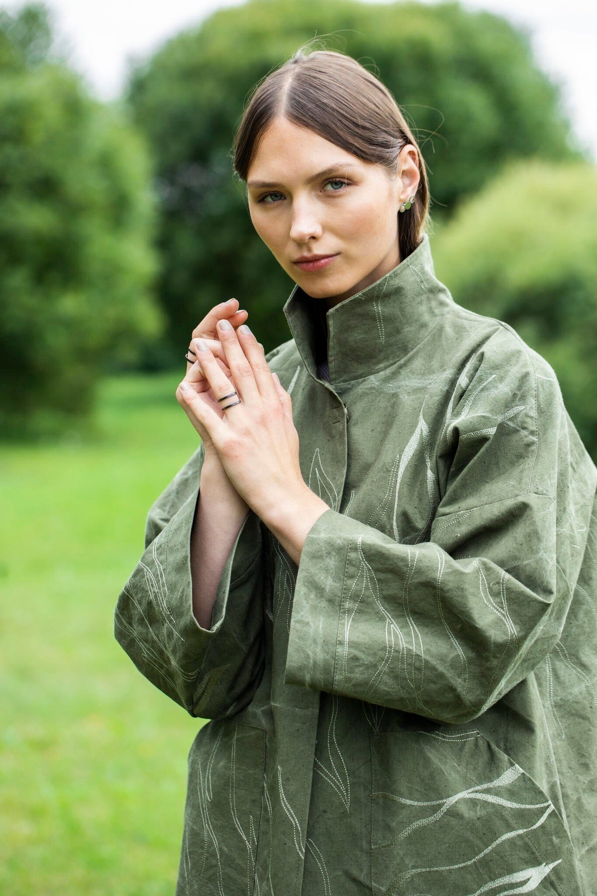 1. Woman wearing Lentsius stainless steel ring in a green outdoor setting, dressed in a green coat