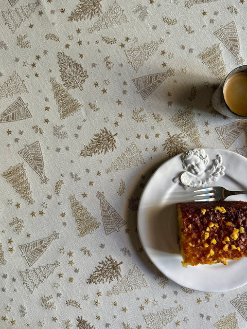5. Detail of Golden Forest tablecloth with golden tree patterns, set with cake and coffee, enhancing festive dining experience