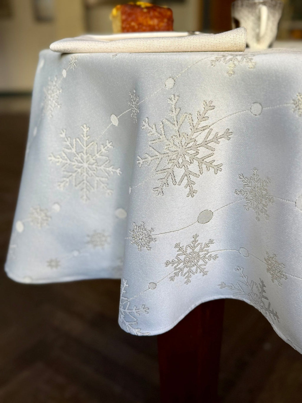 1. Elegant dining setup with Hortensias Home Golden Snowfall tablecloth, golden snowflake design, cake slice, and glass on table