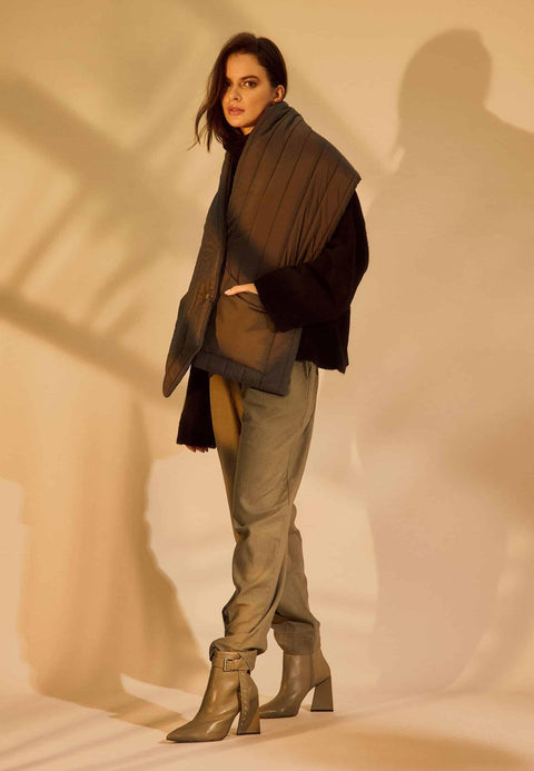 2. Woman wearing salvia green leather ankle boots with pointed toe and side buckle, styled with casual pants in warm lighting