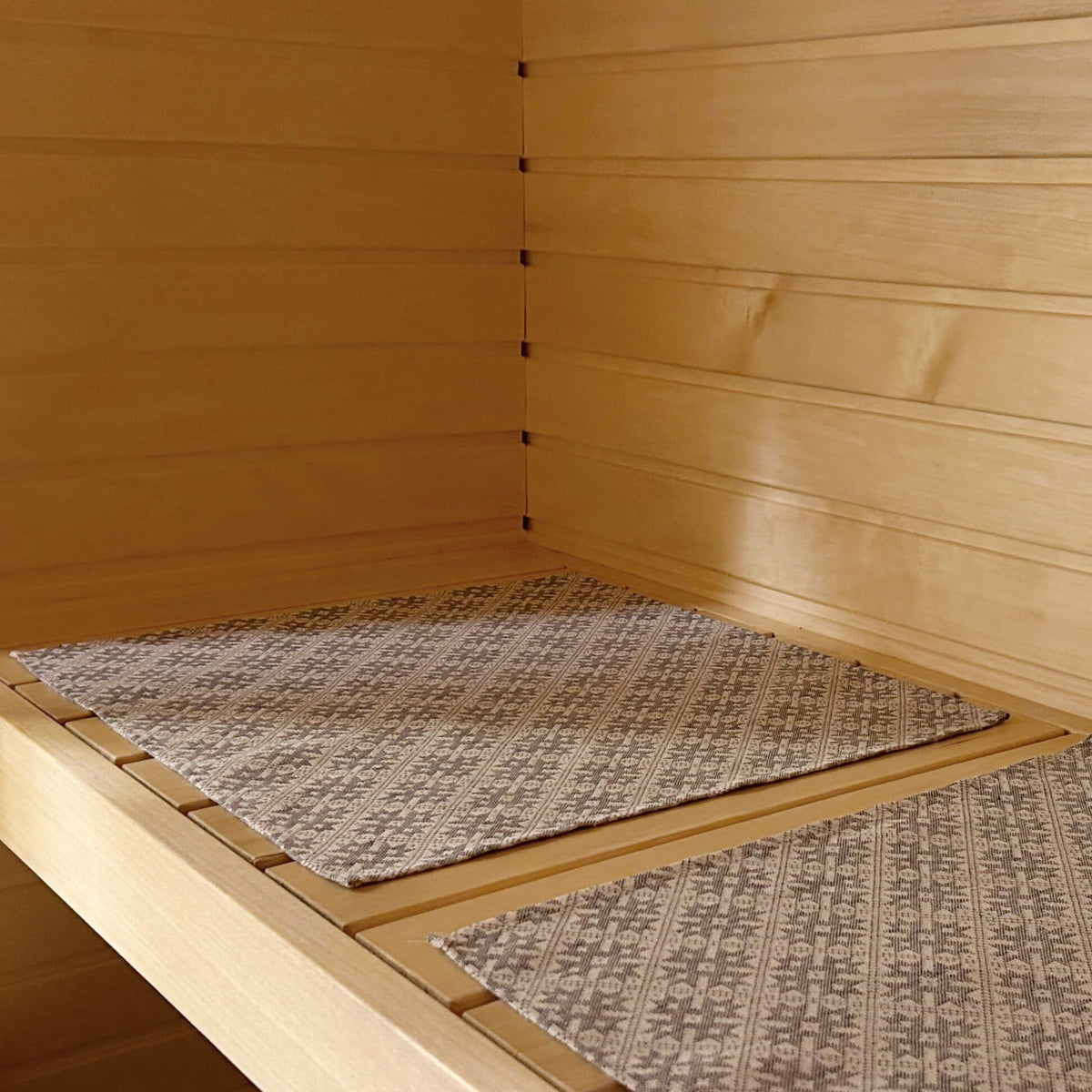3. LOKO sauna seating pad on wooden bench showing traditional Pärnu County mitten pattern