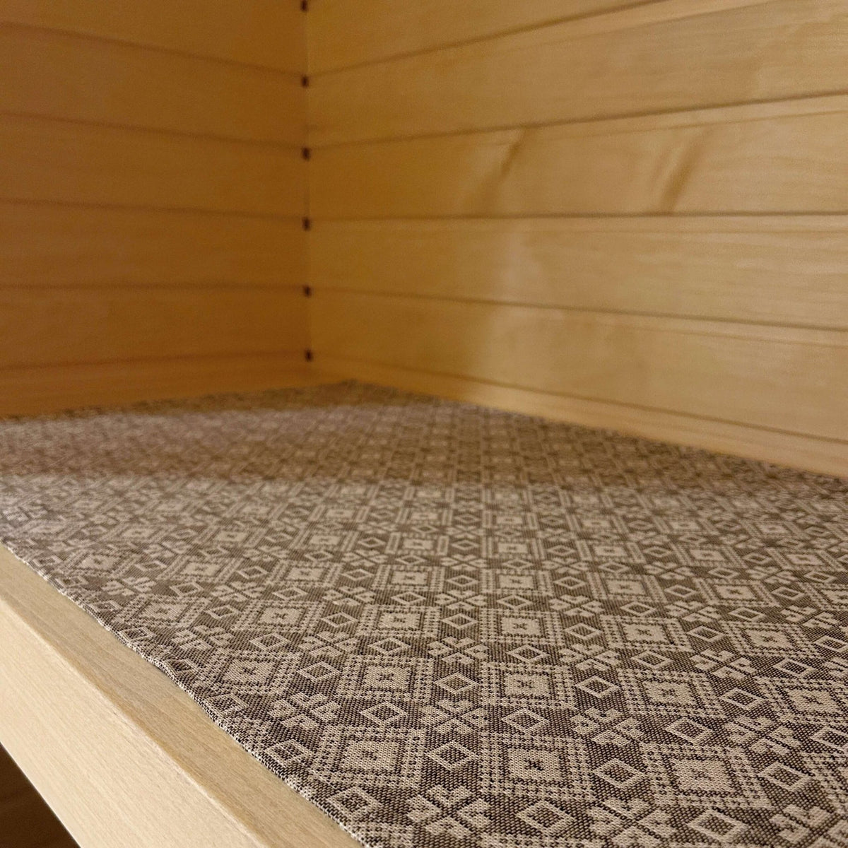 3. Close-up of grey and white patterned sauna bench seating pad on wooden bench, highlighting traditional design.