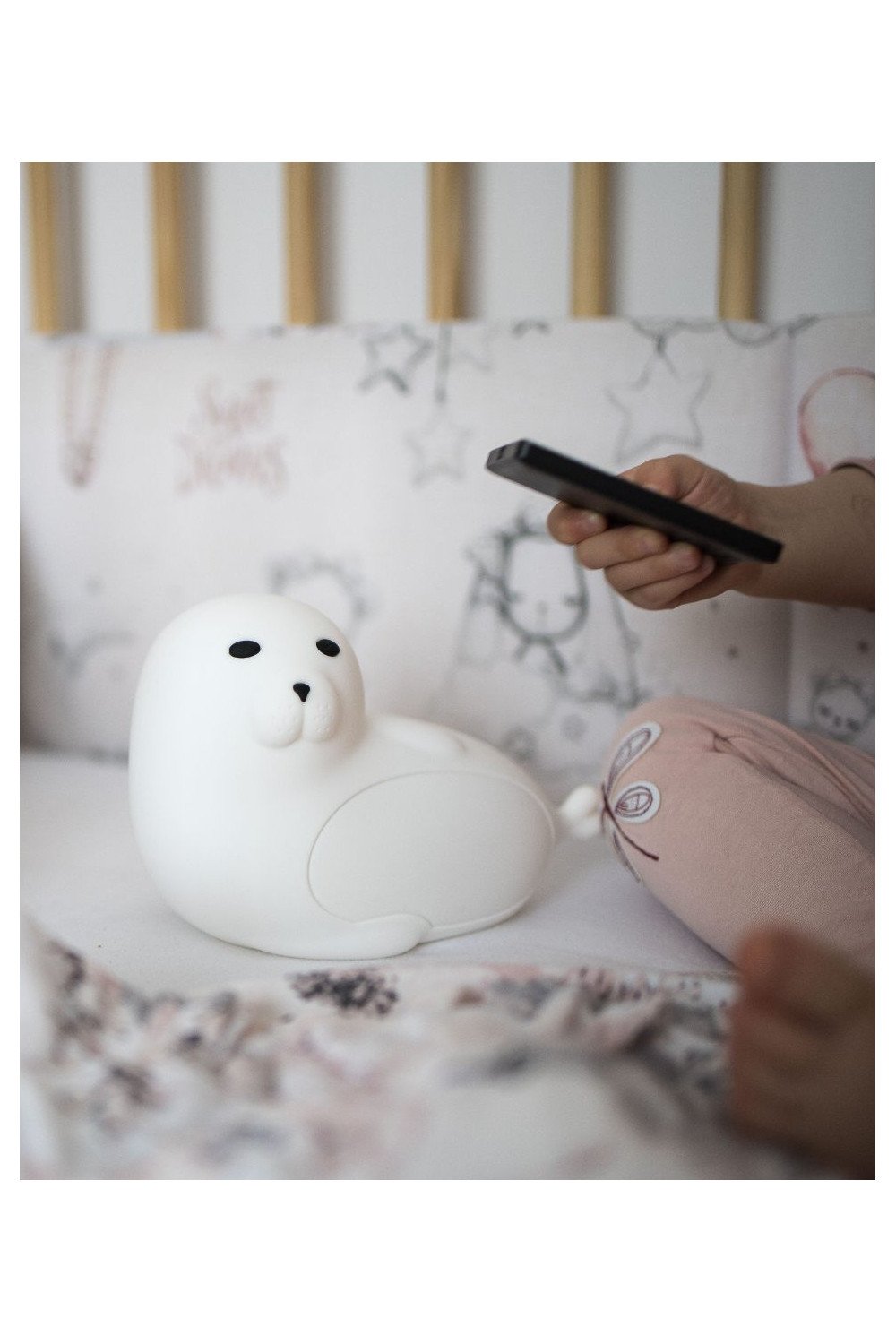 1. Child holding white seal-shaped lamp with remote control on bed