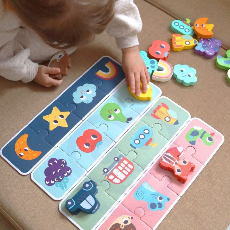 1. Child playing with Woopie Green sensory puzzle on beige couch, matching colorful animal and vehicle shapes on puzzle cards