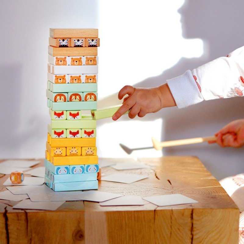9. Child using wooden hammer to play Shaky Tower game with pastel animal blocks