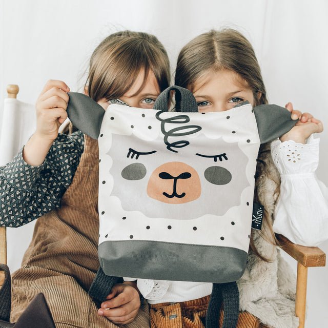 7. Two girls holding Muni sheep backpack, highlighting the cute sheep face and velvet fabric