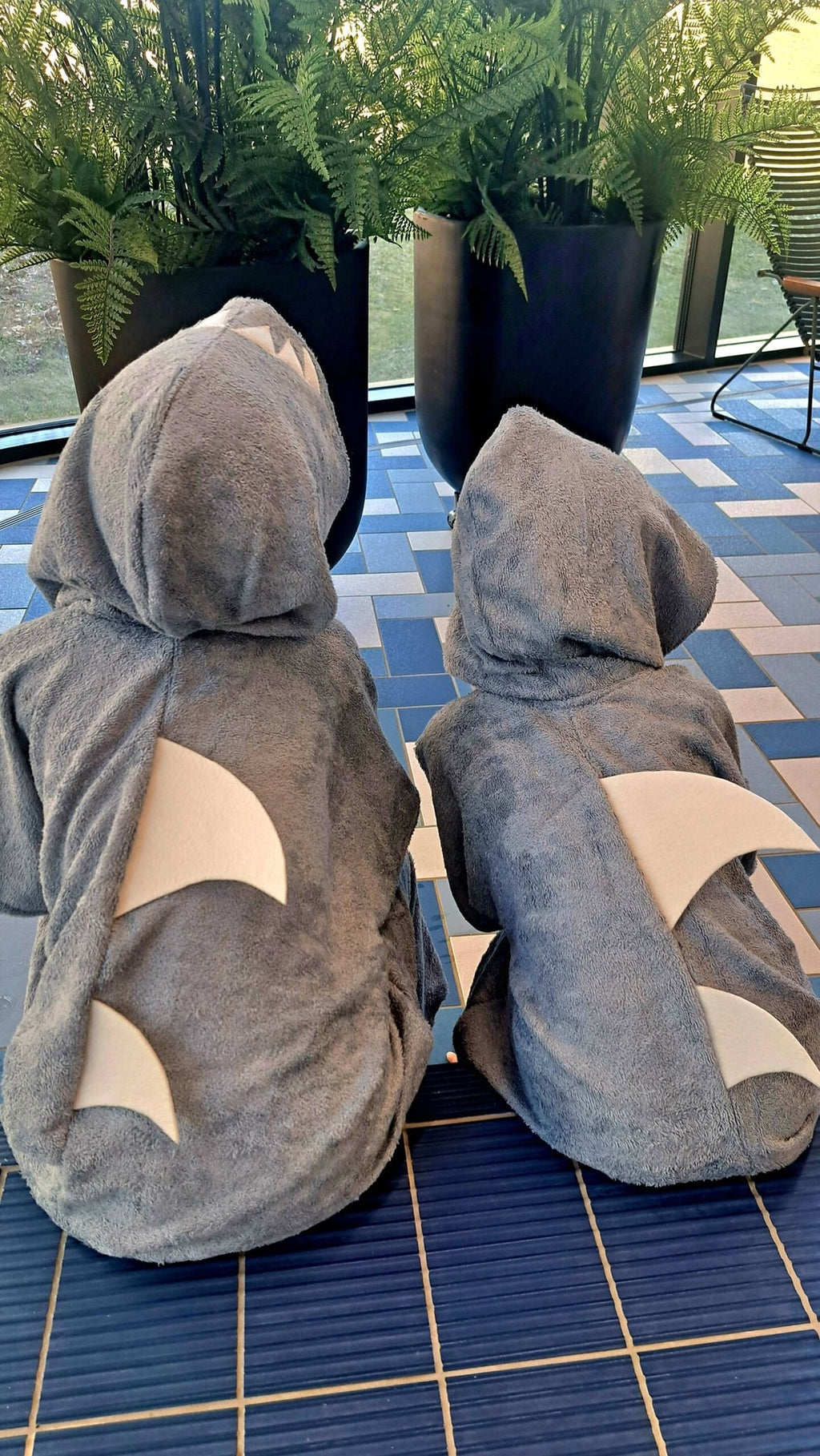 4. Back view of two kids in RÄTT Short-Sleeve Poncho SHARK, emphasizing shark fin and hood
