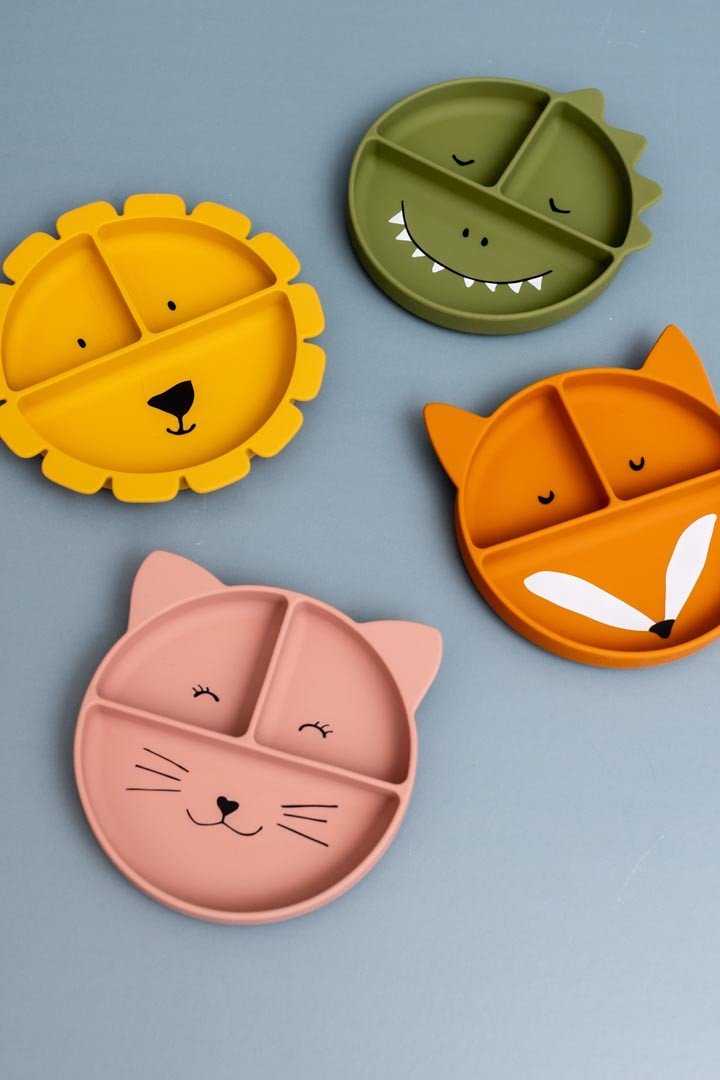 4. Flat lay of four animal-themed silicone plates including fox, lion, cat, and dinosaur designs on a blue background.