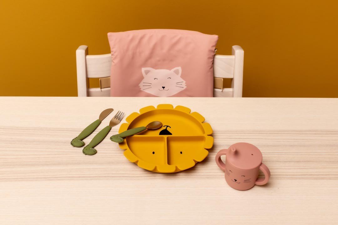 4. Yellow lion-shaped silicone plate with green utensils and pink cup on a wooden table