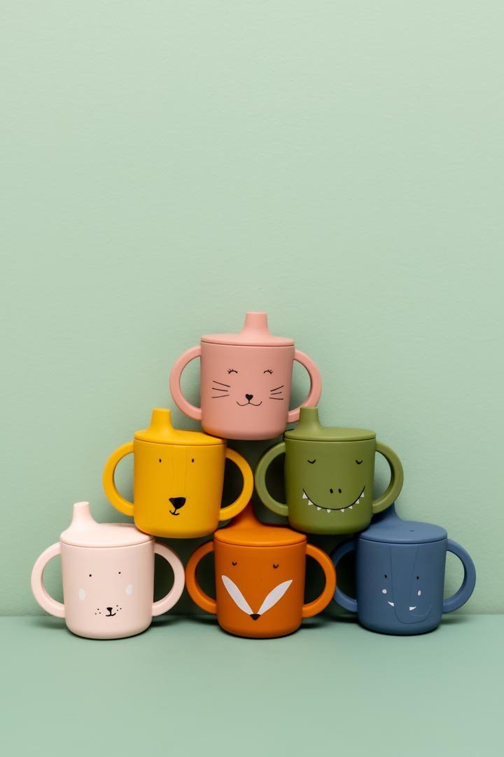 1. Pyramid stack of colorful animal-themed silicone sippy cups against green background