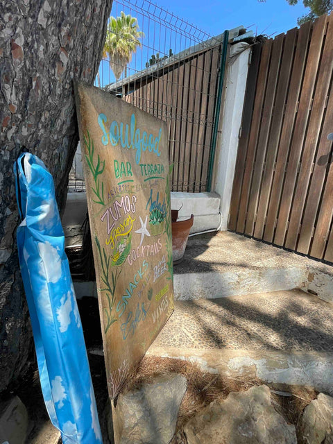 3. Blue carrying case with sky and cloud design next to colorful sign at outdoor terrace