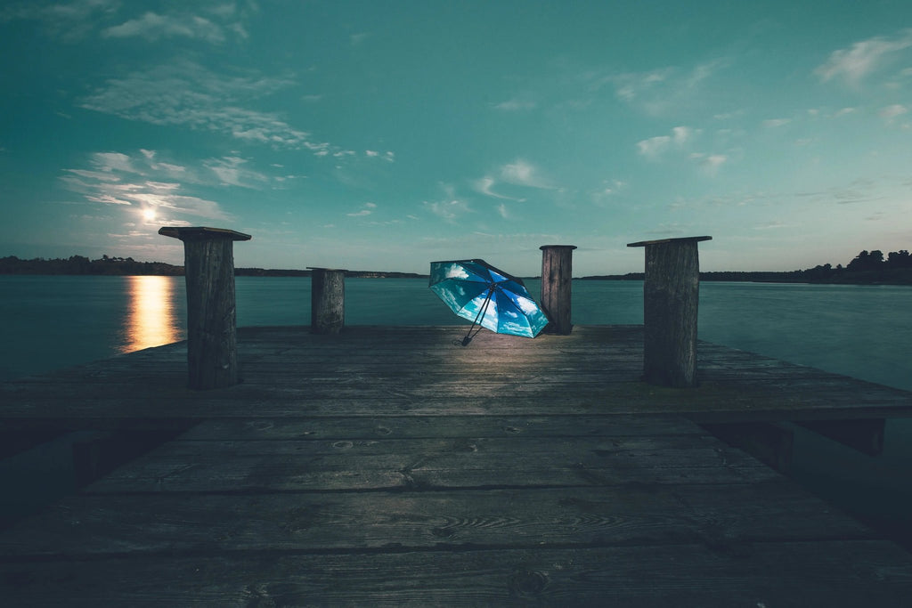 11. Sky Lake umbrella with blue cloud print on wooden dock by lake at dusk