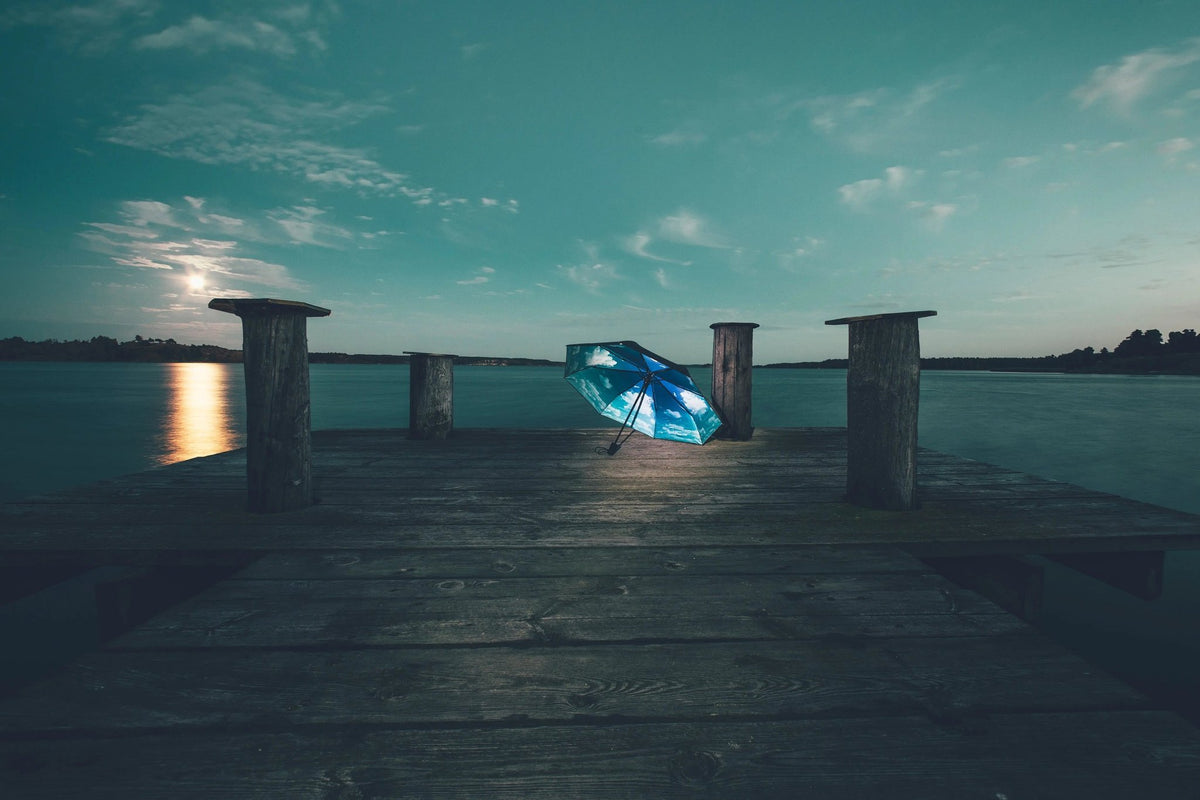 11. Sky Lake umbrella with blue cloud print on wooden dock by lake at dusk