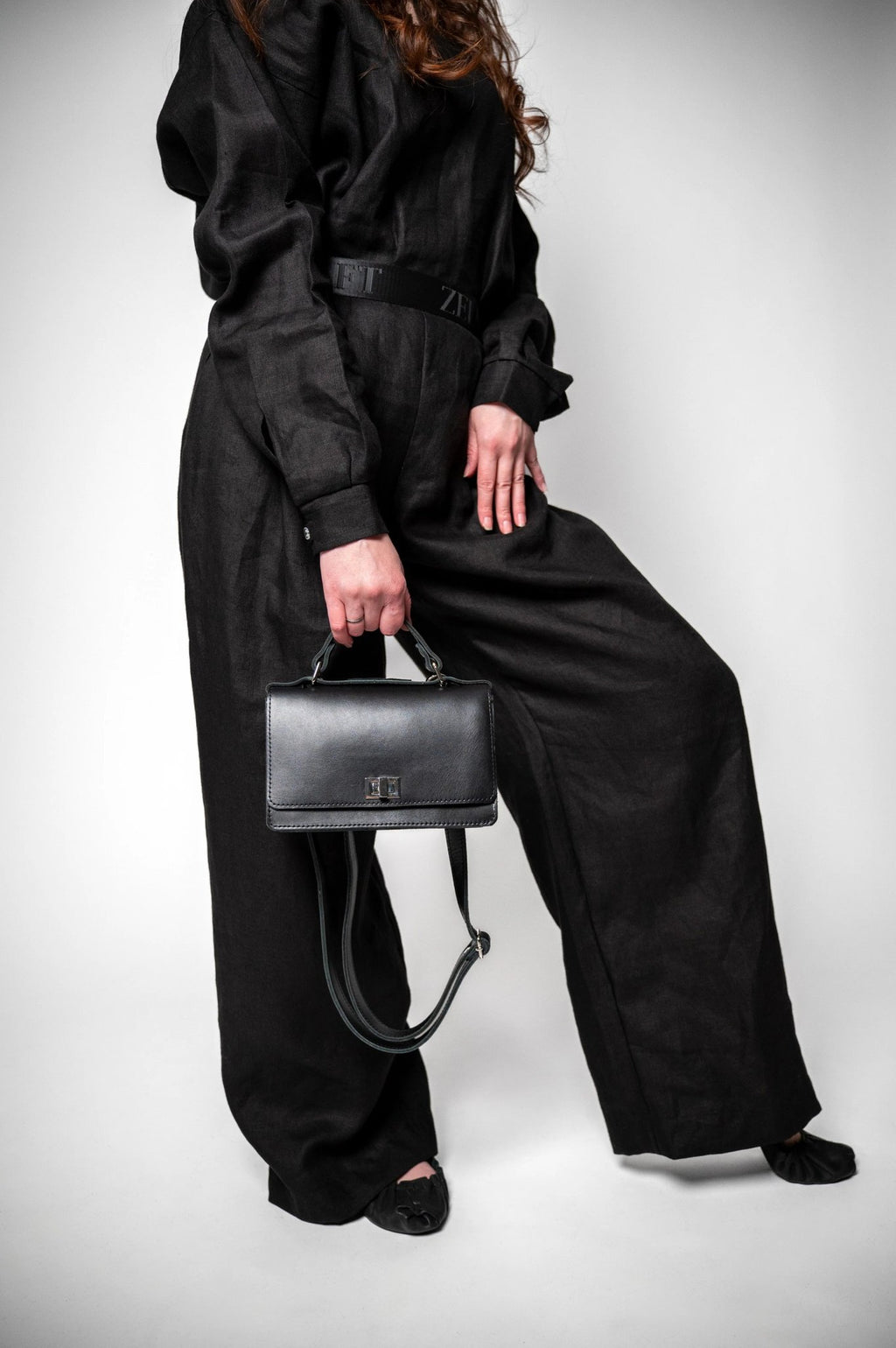 8. Woman in black outfit holding Zelma Kraft black handbag with adjustable strap