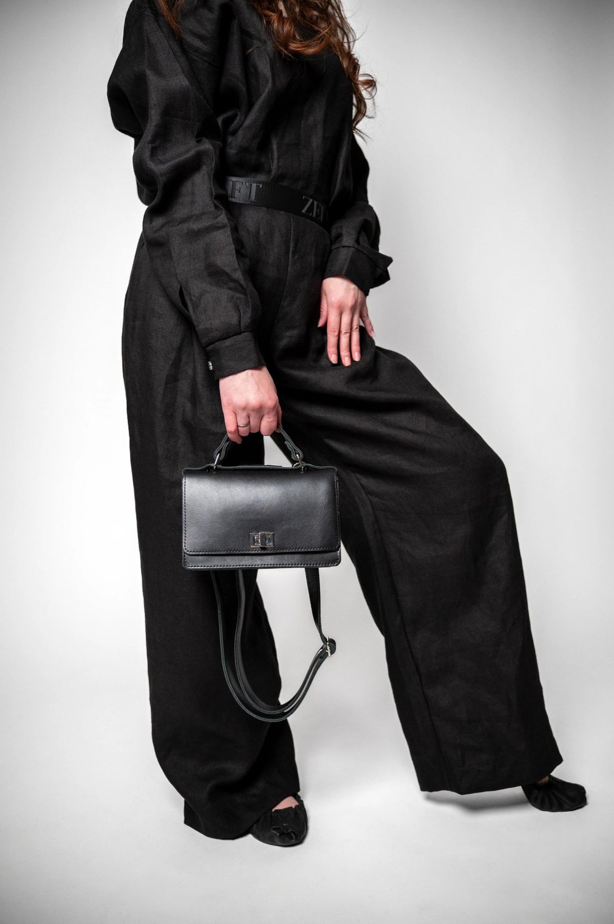 8. Woman in black outfit holding Zelma Kraft black handbag with adjustable strap