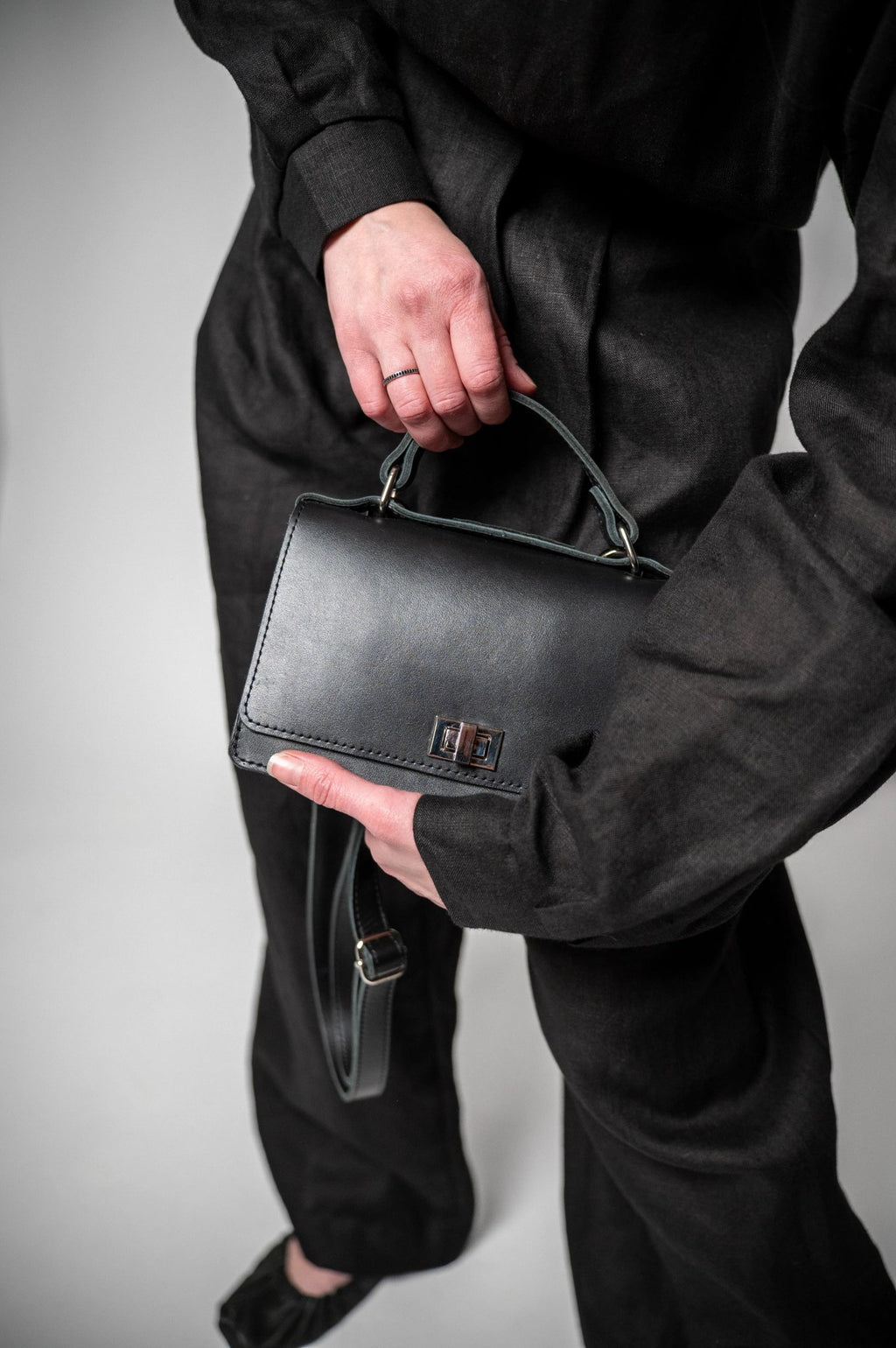9. Woman showcasing Zelma Kraft black handbag with silver clasp in studio setting