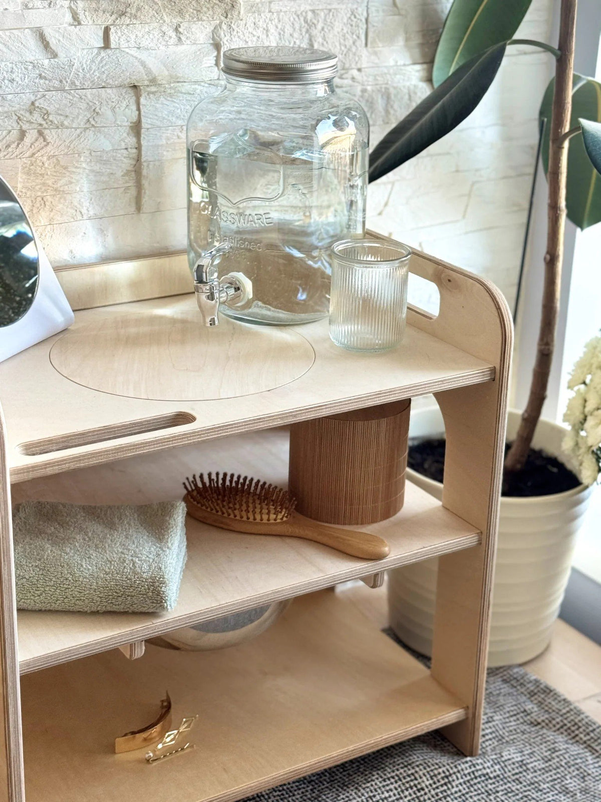 5. Close-up of Montessori wash station with lid, brush, and towel on shelf