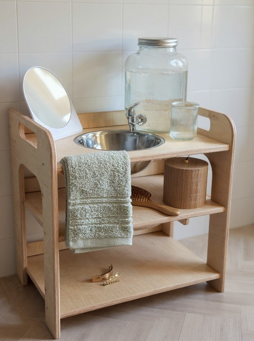 4. Montessori wash station with enamel bowl and towel against white tiled wall